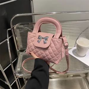 Detail of pink quilted handbag featuring a polished silver bow hardware and top handle
