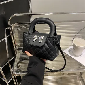 Detailed view of black quilted handbag featuring a silver metallic bow and round handle