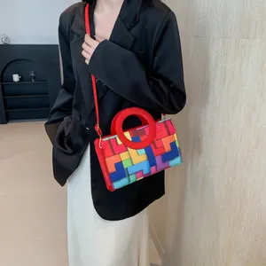 Colorful geometric patchwork square bag with red circular handle and gold hardware detail