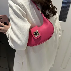 Close-up of rose red crescent bag featuring a decorative golden flower buckle detail