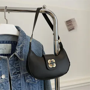 Detail of black leather crescent hobo bag with gold clover clasp and shoulder strap