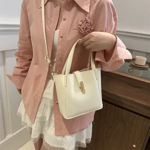 Détail du sac seau en cuir crème avec fermoir doré et bandoulière amovible réglable