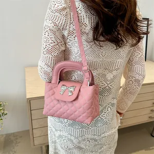 Quilted pink crossbody bag with silver bow accent shown on a model in lace dress