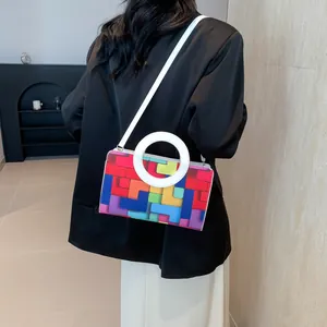 Detail view of the colorful geometric pattern and white round handle on the crossbody bag