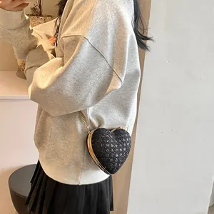 Détail d'un sac à bandoulière en forme de cœur avec paillettes noires et chaîne dorée