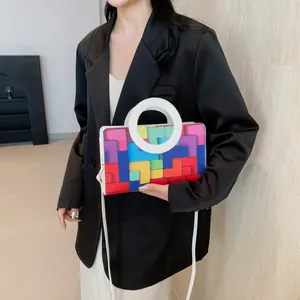 Detail of colorful geometric patchwork crossbody bag with round handle on model