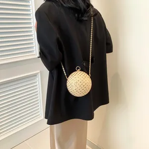 Detailansicht der gewebten Kugel-Handtasche mit goldener Kette und rundem Metallgriff