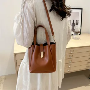 Vue détaillée du sac seau marron sur modèle avec boucle dorée et bandoulière en cuir