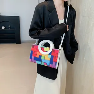 Close-up of a vibrant geometric patchwork crossbody bag with a unique round handle