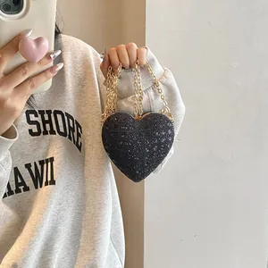 Détail du sac bandoulière en forme de cœur avec paillettes noires et chaîne dorée