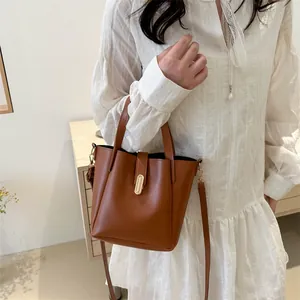 Sac seau en cuir marron avec fermoir métallique doré et bandoulière amovible