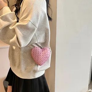 Vue macro d'un sac à main rose en forme de cœur avec cristaux et chaîne dorée élégante