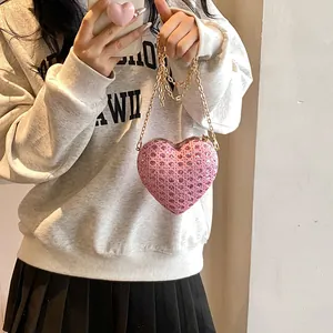 Sac bandoulière pailleté rose en forme de cœur avec chaîne en métal sur un mannequin