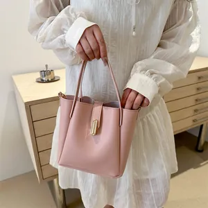Détail d'un sac seau rose avec boucle dorée porté par un mannequin en robe blanche