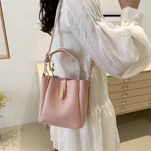 Sac seau en cuir rose avec boucle dorée porté par un mannequin dans un salon chic
