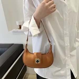 Brown leather crescent shoulder bag featuring a gold clover buckle and retro matte finish