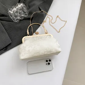 Detail of vintage ivory jacquard handbag with golden kiss-lock and chain strap