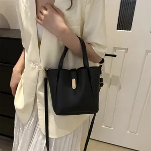 Gros plan sur un sac seau en cuir noir avec boucle dorée et bandoulière réglable