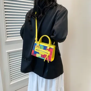 Fashionable color-block crossbody bag with decorative tassels and yellow handle on a model