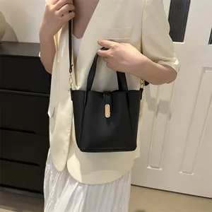 Détails du sac seau noir avec une boucle dorée élégante et une texture en cuir mat