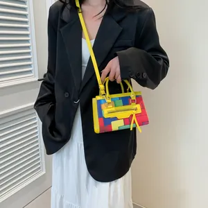 Detail of color-block patchwork mini handbag featuring yellow straps and tassel zipper