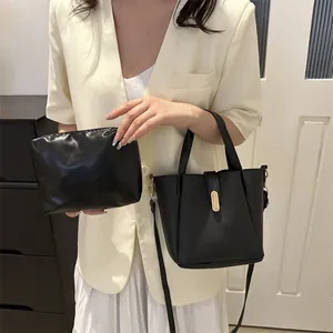 Gros plan du sac seau rétro noir avec boucle dorée et pochette assortie en cuir