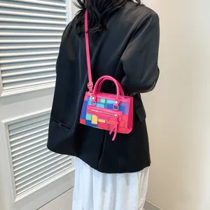 Colorful geometric patchwork mini bag styled on a black blazer and white skirt
