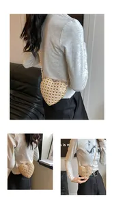 Détail du sac en paille tressée en forme de cœur avec une élégante bandoulière dorée