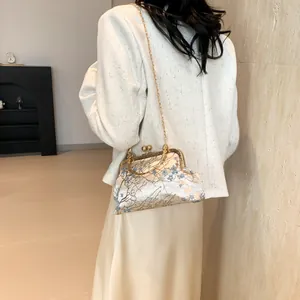 Détail du sac coquillage en brocart floral avec fermoir doré et bandoulière