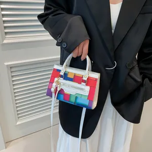 Detail of color-block geometric small square bag with colorful pattern and gold hardware