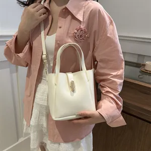 Sac seau élégant en cuir PU blanc crème avec boucle en métal doré dans un contexte chic