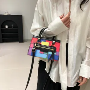 Close-up of geometric color-block crossbody bag featuring gold zippers and black straps