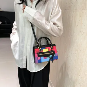 Detail of colorful geometric patchwork handbag with gold hardware worn by a model