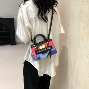 Detail of colorful geometric patchwork mini handbag with round top handle and crossbody strap