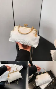Macro view of white floral jacquard handbag with gold kiss-lock and metal handle