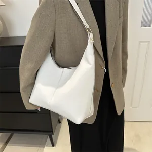 Minimalistische weiße Hobo-Tasche am Modell mit glatter Lederstruktur und goldener Schnalle