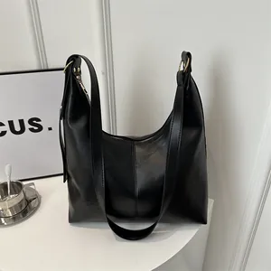 Detail der schwarzen Hobo-Tasche mit goldener Hardware und breiten Schultergurten