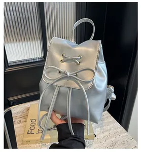 Detailed view of a silver mini backpack with a decorative bow and lace-up design feature
