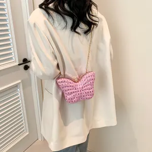 Modelo con bolso de noche de mariposa rosa con pedrería rosa y cadena dorada