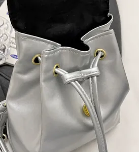 Detail van zilveren metallic rugzak met trekkoordsluiting en gouden oogjes