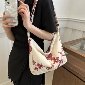 Detail of red floral embroidery on off-white canvas hobo bag with a zipper closure