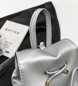 Detail van zilveren PU-lederen rugzak met stevig handvat en gouden metalen ogen