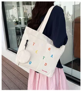 Detail of white canvas tote bag with colorful embroidery and matching small round coin purse