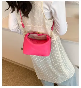 Detail of bright pink crossbody bag with rich rabbit letter embossing and gold hardware