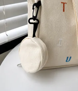 Detailed shot of the detachable small circular coin purse on a beige canvas tote bag