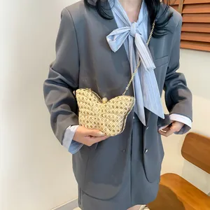 Elegante bolso de noche de mariposa con cadena de oro llevado con un traje gris