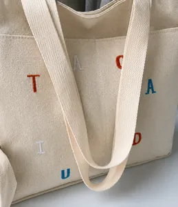 Detailed close-up of premium canvas tote bag with colorful embroidery and side pocket