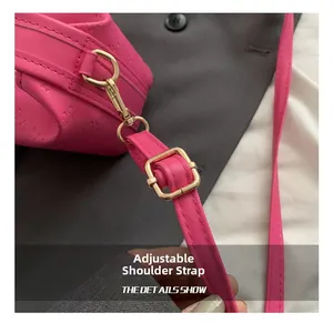 Close-up of adjustable strap with gold metal hardware on rose pink textured handbag