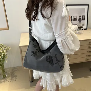 Detail shot of embroidered butterfly pattern on grey canvas shoulder bag for women