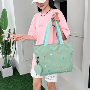 Detail of light green canvas tote bag with colorful letter embroidery and mini pouch